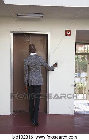 Stock Photography - African businessman pushing elevator button. Fotosearch
