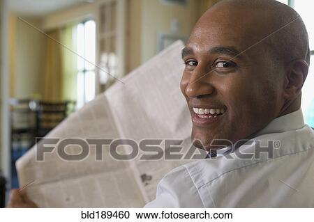Stock Image - African businessman reading newspaper. Fotosearch