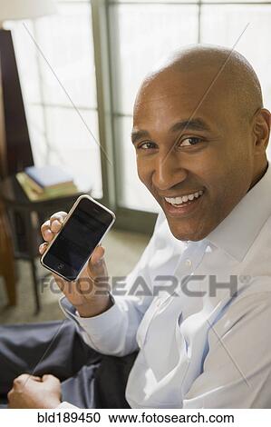 Stock Image - African businessman showing cell phone. Fotosearch