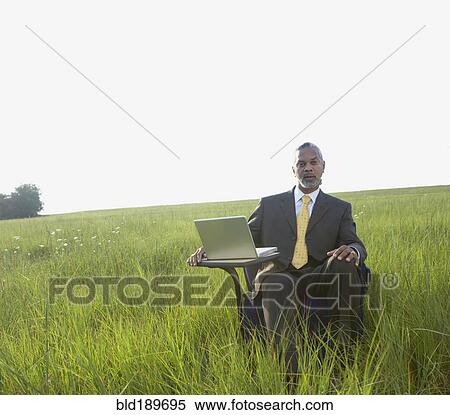 African businessman sitting with laptop in field View Large Photo Image Stock Photography - African businessman sitting with laptop in field. Fotosearch