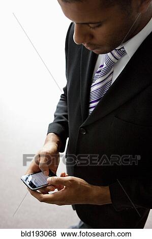 African businessman text messaging on cell phone View Large Photo Image Stock Photo - African businessman text messaging on cell phone. Fotosearch