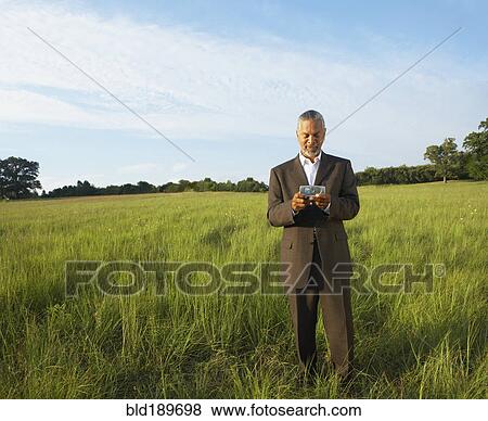 African businessman using electronic organizer in field View Large Photo Image Stock Photo - African businessman using electronic organizer in field. Fotosearch