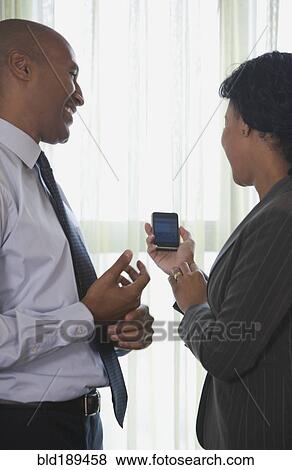 Stock Photo - African businesspeople looking at cell phone. Fotosearch