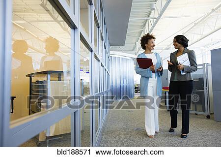 Stock Image - African businesswoman walking down office corridor. Fotosearch
