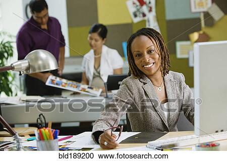 Stock Image - African businesswoman working at desk. Fotosearch