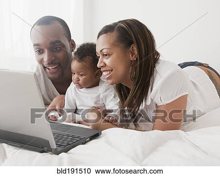 African couple and baby using laptop on bed View Large Photo Image Stock Image - African couple and baby using laptop on bed. Fotosearch