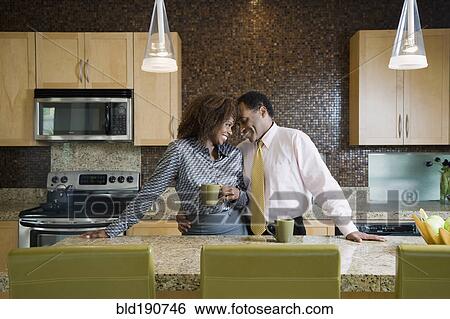 Stock Photograph - African couple drinking coffee in modern kitchen. Fotosearch