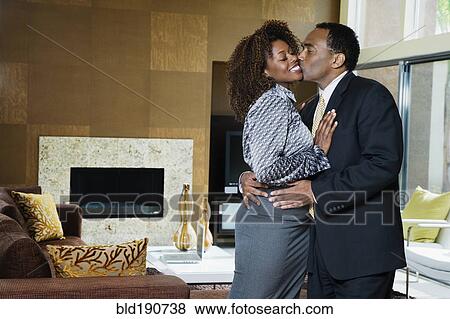 Stock Photo - African couple kissing in modern living room. Fotosearch