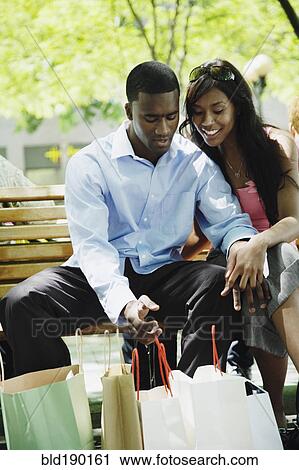 Stock Image - African couple looking at shopping bags. Fotosearch