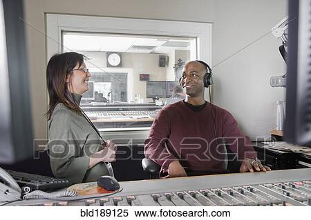 Stock Photography - African dj working at radio station with co-worker. Fotosearch