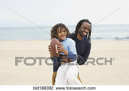 Stock Image - African father an son playing football. Fotosearch