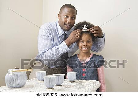 Stock Photograph - African father and daughter posing with tiara. Fotosearch