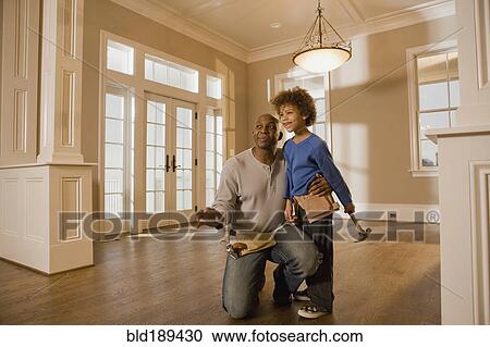 Stock Image - African father and son wearing tool belts. Fotosearch