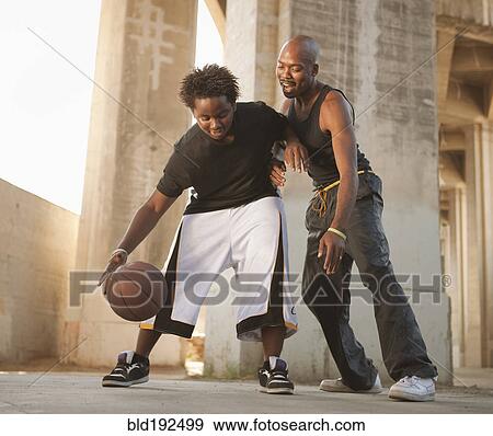 Stock Photo - African father playing basketball with son. Fotosearch