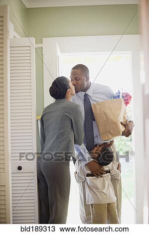 Stock Image - African father with groceries greeting family. Fotosearch