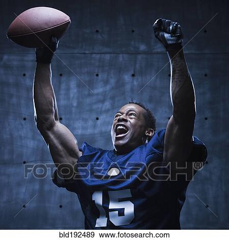 Stock Photo - African football player cheering with arms raised. Fotosearch