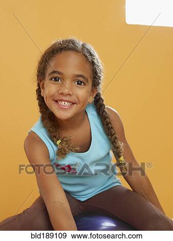 Stock Photo - African girl sitting on exercise ball. Fotosearch
