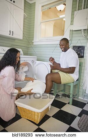 Stock Image - African husband helping wife fold laundry. Fotosearch