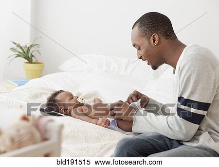 African man changing baby's diaper on bed View Large Photo Image Stock Photography - African man changing baby's diaper on bed. Fotosearch