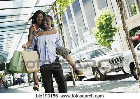 Stock Photograph - African man giving girlfriend piggyback ride. Fotosearch
