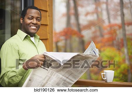 Stock Photograph - African man reading newspaper outdoors. Fotosearch