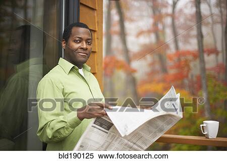 Stock Photography - African man reading newspaper outdoors. Fotosearch