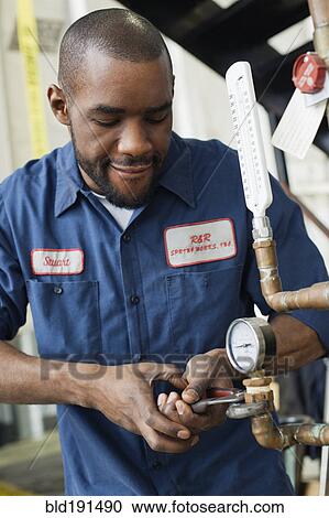 Stock Image - African man repairing valve. Fotosearch