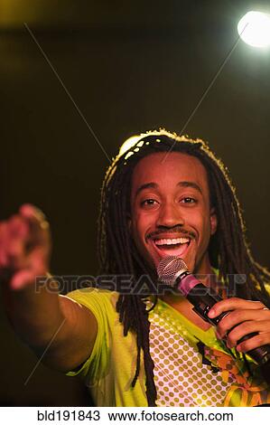 Stock Image - African man singing on stage. Fotosearch