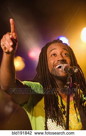 Stock Image - African man singing onstage. Fotosearch