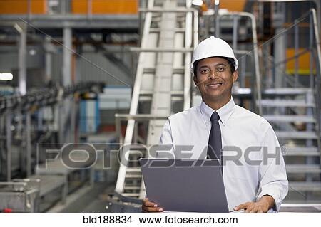 Picture - African manager with laptop in factory. Fotosearch