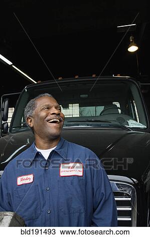 Stock Image - African mechanic standing in front of truck. Fotosearch