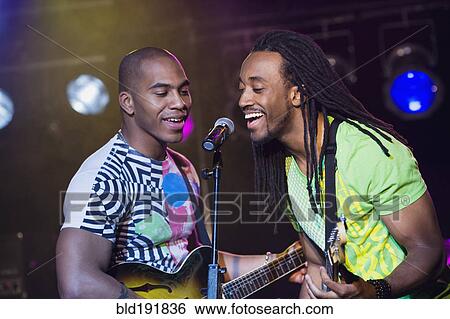 Stock Photograph - African men singing and playing guitar onstage. Fotosearch