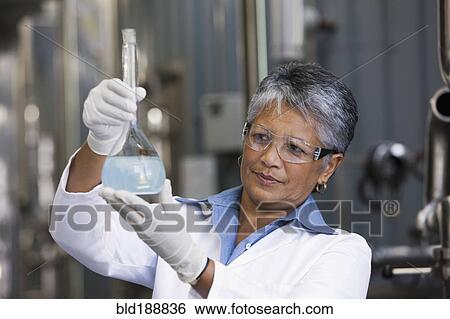 Stock Photograph - African scientist examining beaker of liquid in factory. Fotosearch