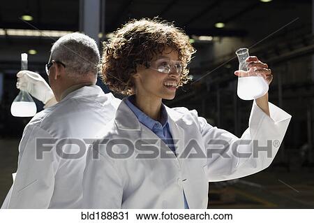 Stock Image - African scientists examining beakers of liquid in factory. Fotosearch