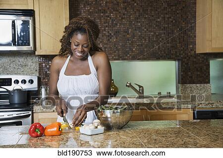 Stock Image - African woman fixing healthy meal in modern kitchen. Fotosearch