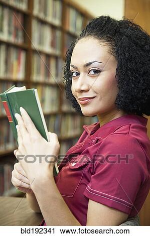 Stock Image - African woman reading book in library. Fotosearch