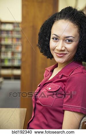 Stock Image - African woman smiling in library. Fotosearch