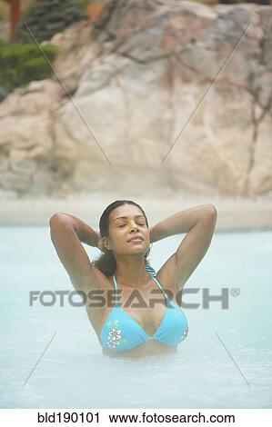 Stock Image - African woman standing in hot tub. Fotosearch