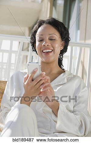 Stock Photo - African woman using cell phone on balcony. Fotosearch