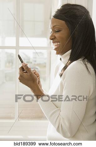 Stock Photo - African woman using cell phone. Fotosearch