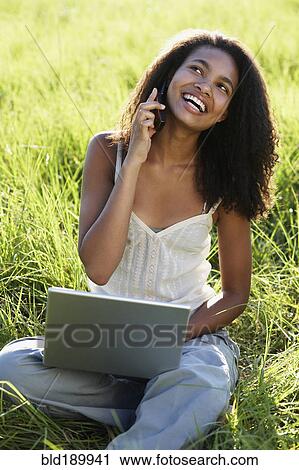 African woman using laptop and cell phone in meadow View Large Photo Image Stock Image - African woman using laptop and cell phone in meadow. Fotosearch