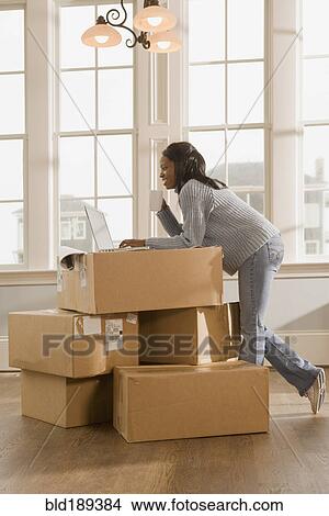 Picture - African woman using laptop on boxes. Fotosearch