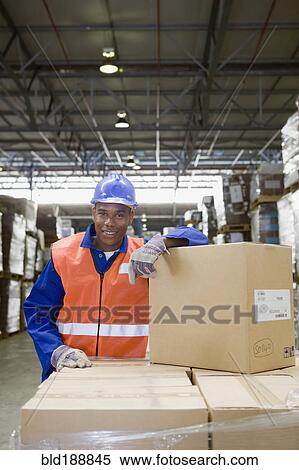 Stock Photography - African worker leaning on boxes in warehouse. Fotosearch