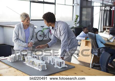 Stock Image - Architects examining architectural model in office. Fotosearch