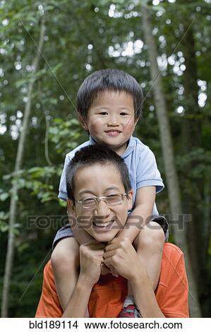 Picture - Asian boy carrying brother on shoulders. Fotosearch