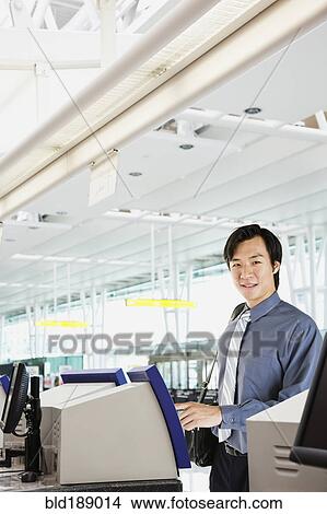 Picture - Asian businessman checking in at airport. Fotosearch
