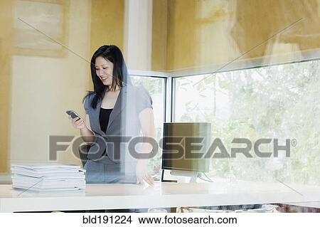 Picture - Asian businesswoman looking at cell phone. Fotosearch