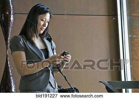 Stock Photo - Asian businesswoman looking at cell phone. Fotosearch