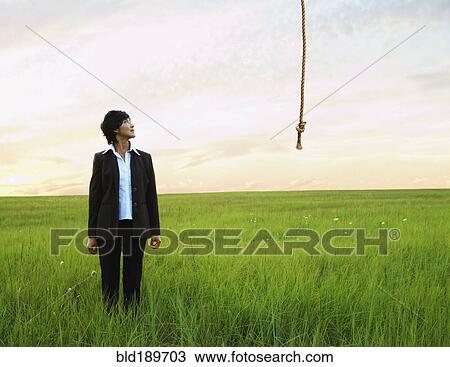 Stock Image - Asian businesswoman looking at rope in field. Fotosearch