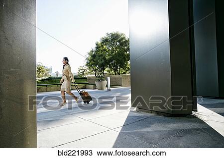 Asian businesswoman rolling luggage outdoors View Large Photo Image Stock Image - Asian businesswoman rolling luggage outdoors. Fotosearch